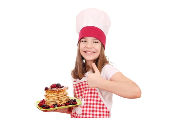 Menina feliz cozinhar com panquecas e polegar para cima — Fotografia de Stock