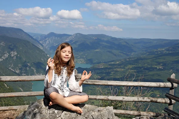 Krásná holčička meditující na vrcholu hory — Stock fotografie