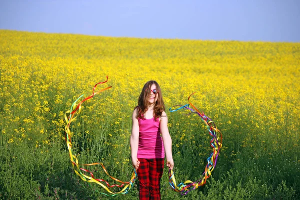 Feliz niña saludando con cintas de colores en campo primavera s — Foto de Stock