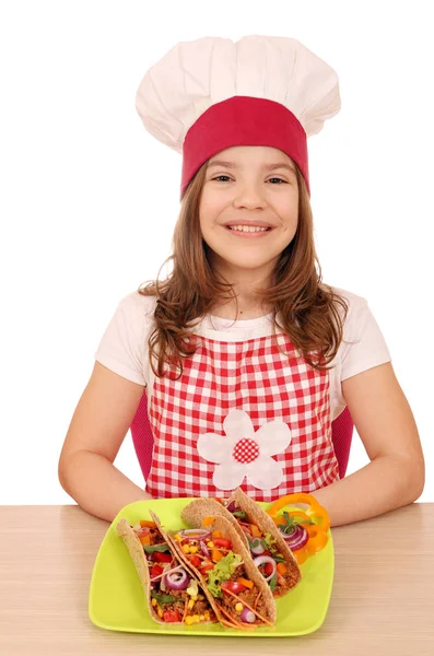 Menina feliz cozinhar com tacos na mesa — Fotografia de Stock