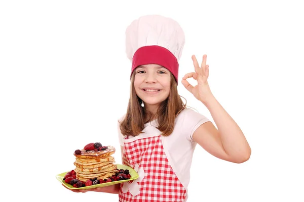 Feliz niña cocinero con panqueques y ok signo de mano —  Fotos de Stock