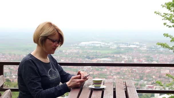 Žena pití kávy a hrát si s chytrý telefon — Stock video