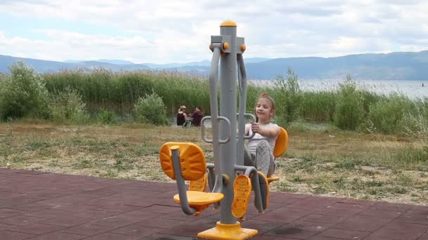 Niña ejercicio al aire libre en el equipo de fitness — Vídeos de Stock