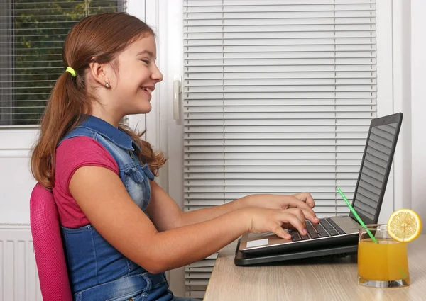 Счастливая маленькая девочка играет на ноутбуке — стоковое фото