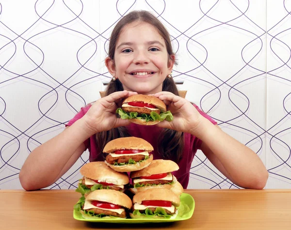 Glückliches kleines Mädchen mit Hamburgern — Stockfoto