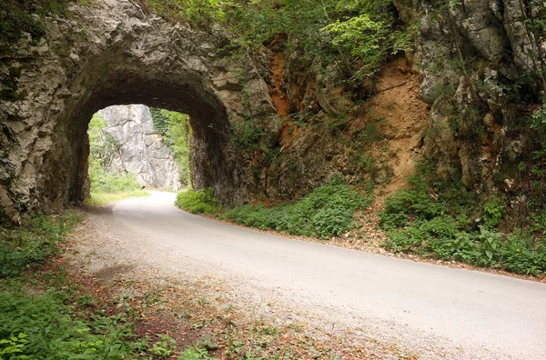 The mountain road passes through a stone tunnel landscape — Stock Photo, Image