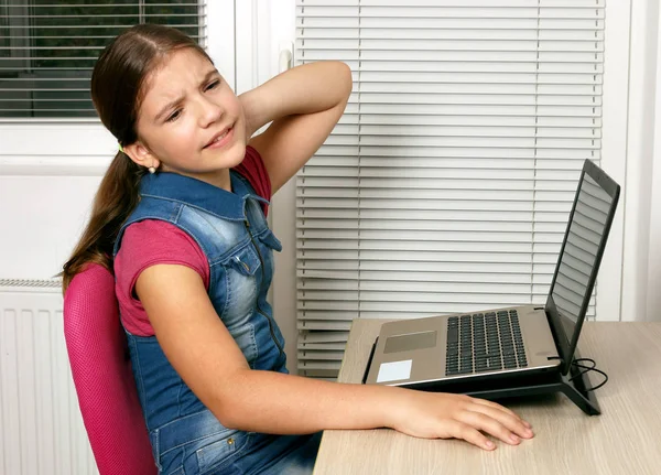Olycklig liten flicka har smärta i nacken när du använder en bärbar dator — Stockfoto