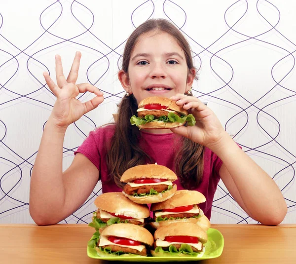 Šťastná holčička s hamburgery a značka ok ruky — Stock fotografie