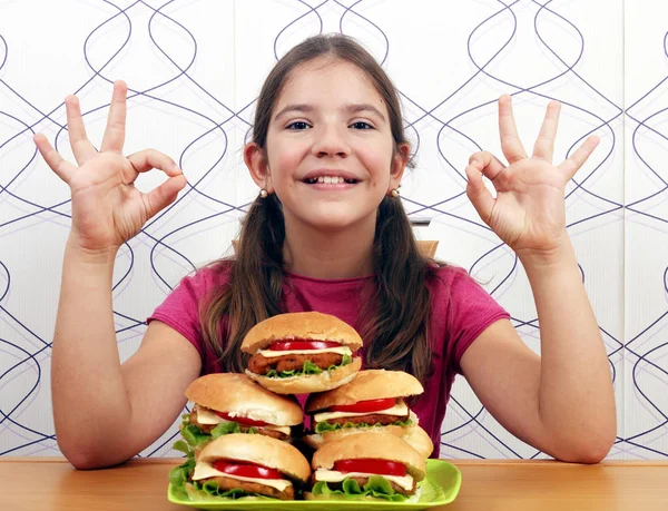 Šťastná holčička s hamburgery a ok rukou znamení — Stock fotografie