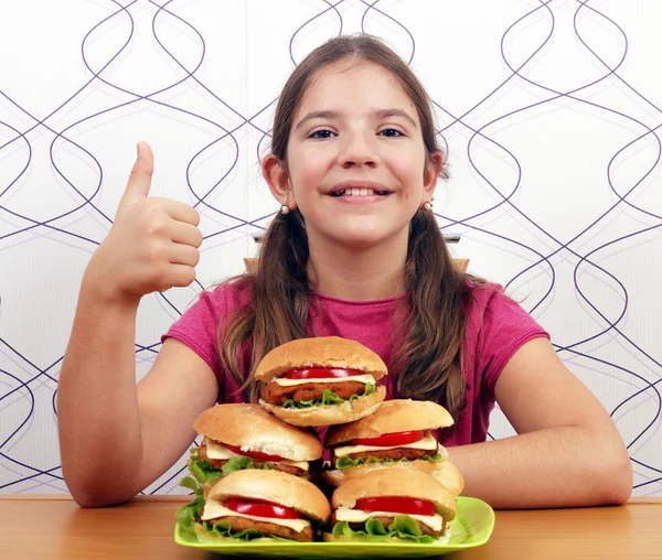 Hamburger ve başparmak ile mutlu küçük kız — Stok fotoğraf