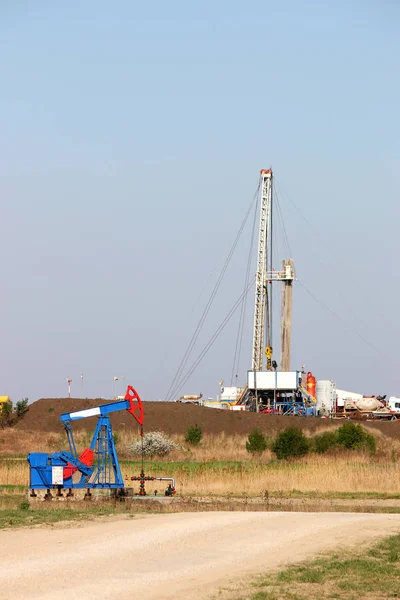 Bomba jack y plataforma de perforación de petróleo en el campo petrolífero — Foto de Stock