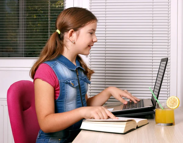 Menina estuda com um livro e um laptop — Fotografia de Stock