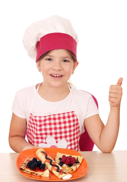 Happy little girl cook with crepes and thumb up — Stock Photo, Image