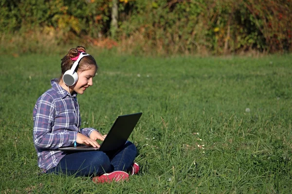 Menina feliz tocando laptop e ouvir música no headphon — Fotografia de Stock
