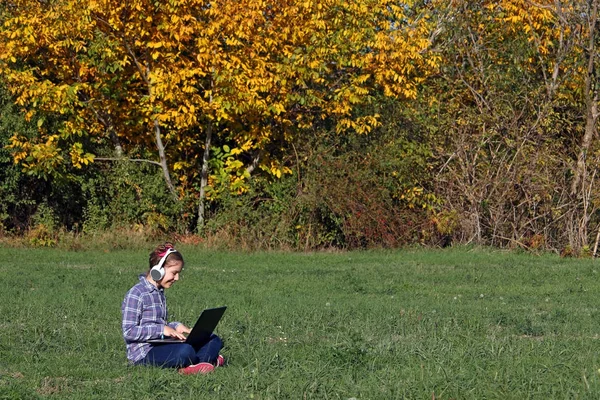 Feliz niña jugando portátil y escuchando música en el auricular —  Fotos de Stock