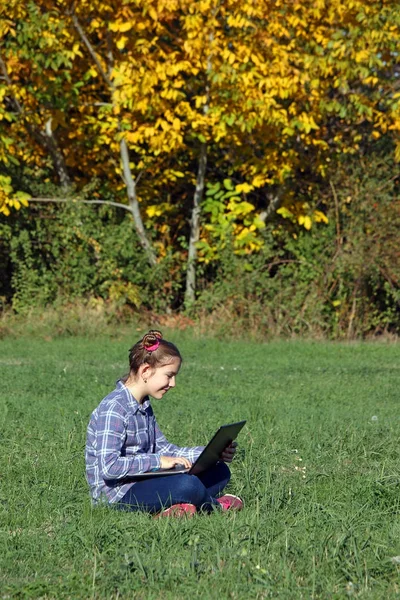 Malá holčička hraje notebook v parku podzimní sezóny — Stock fotografie