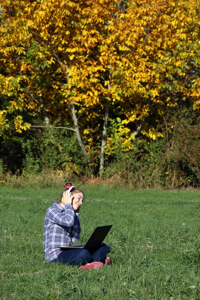 Kleines Mädchen spielt Laptop und hört Musik über Kopfhörer in — Stockfoto