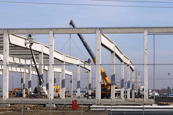 new factory construction site with trucks cranes and workers