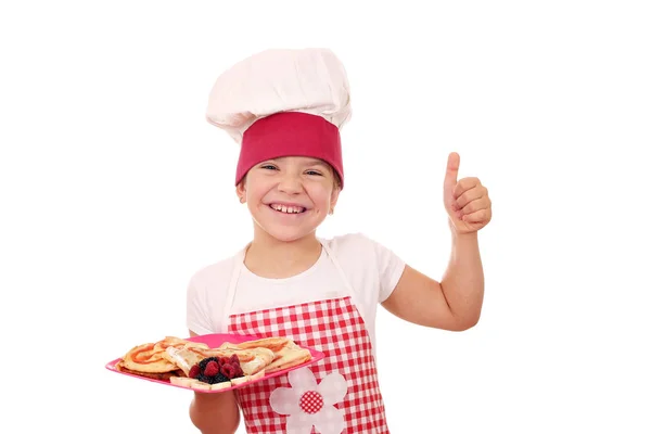 Happy little girl cook with thumb up and sweet crepes — Stock Photo, Image