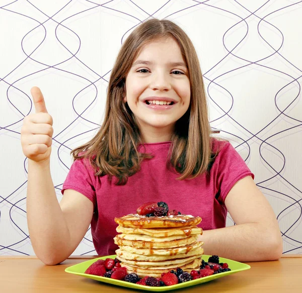 Щаслива маленька дівчинка з панкасками десерт і великий палець вгору — стокове фото