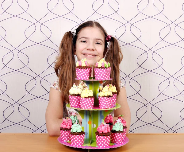 Menina feliz com muffins doces na mesa — Fotografia de Stock