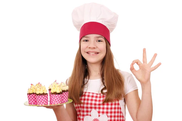 Bonne petite fille cuisinier avec des muffins et ok signe de la main — Photo