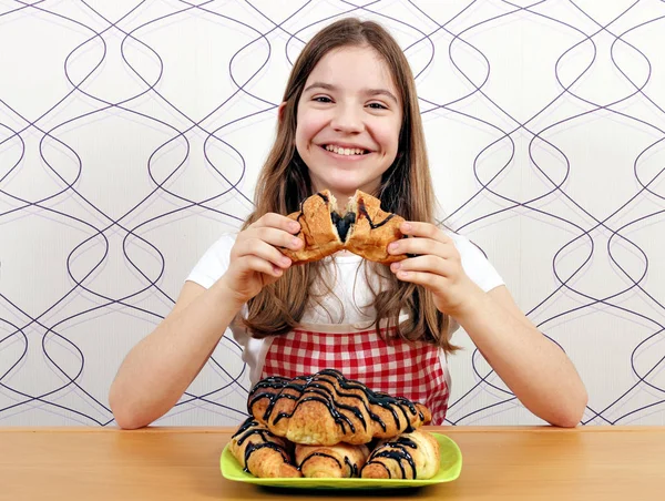 Menina feliz come croissant saboroso com chocolate — Fotografia de Stock