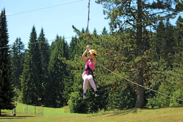 Little girl sliding on a zip line extreme park summer season — Stock Photo, Image