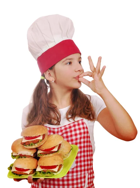 Glückliches kleines Mädchen kocht mit Hamburgern und ok Handzeichen — Stockfoto