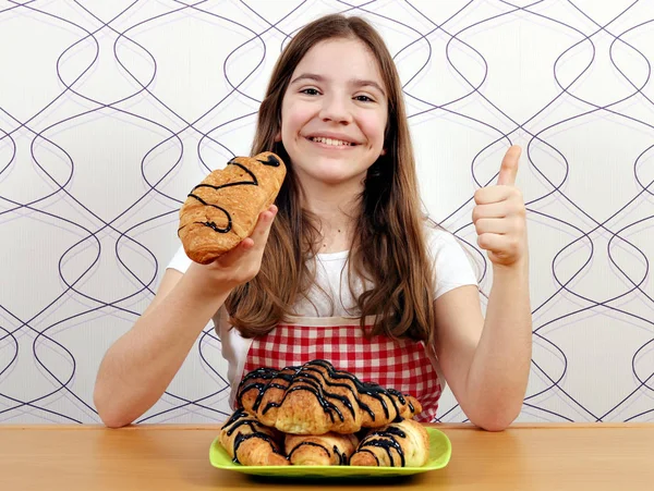 Šťastná holčička s croissanty a palec nahoru — Stock fotografie