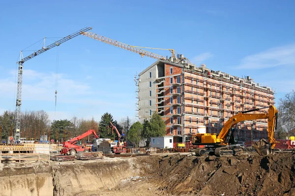 New building construction site with workers cranes and excavator — Stock Photo, Image