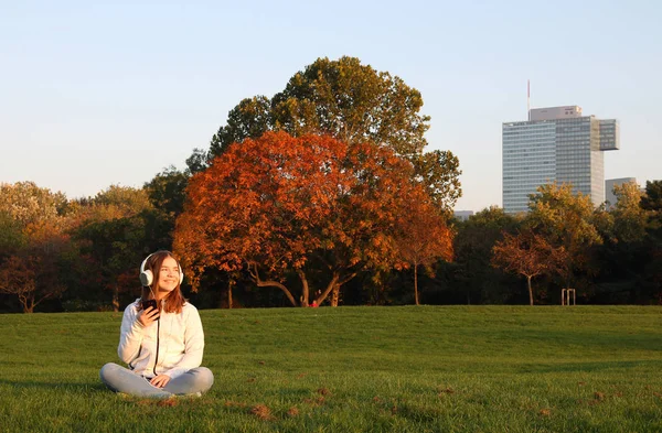 Happy teenage girl listens to music from her smartphone in park — Stock Photo, Image