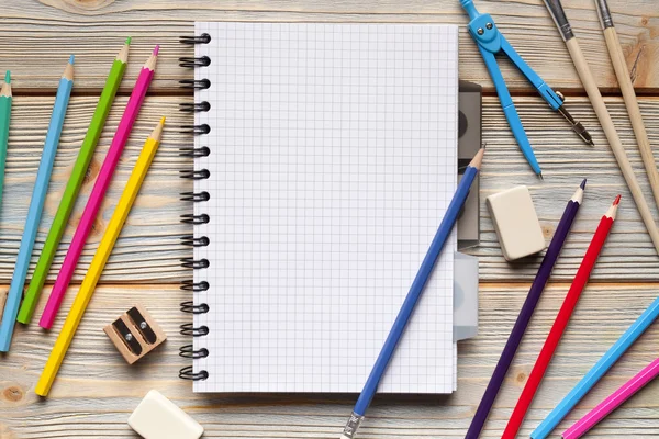 Blocco note e materiale scolastico su tavola di legno — Foto Stock