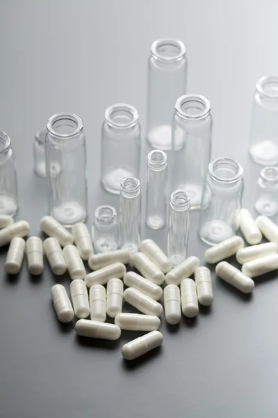 Medicine capsules and glass containers — Stock Photo, Image