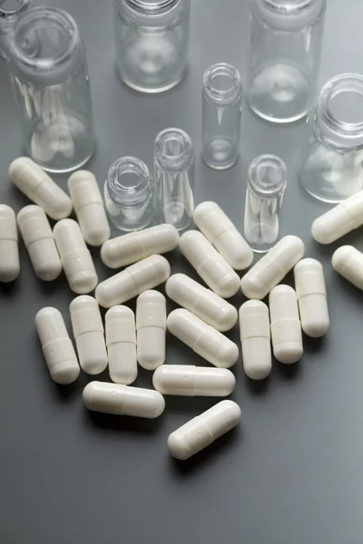 Medicine capsules and glass containers — Stock Photo, Image