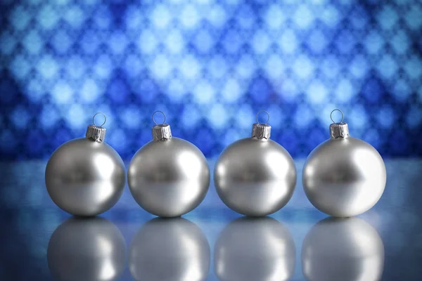 Mavi arka plan üzerinde dört gümüş baubles — Stok fotoğraf