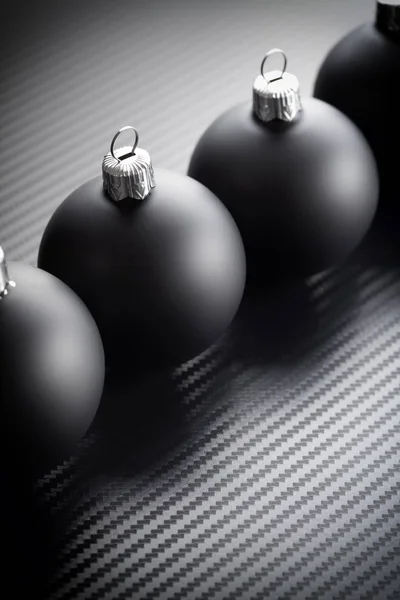 Karbon arka plan üzerinde siyah Noel baubles — Stok fotoğraf