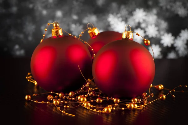 Три красных рождественских безделушки на черном столе — стоковое фото