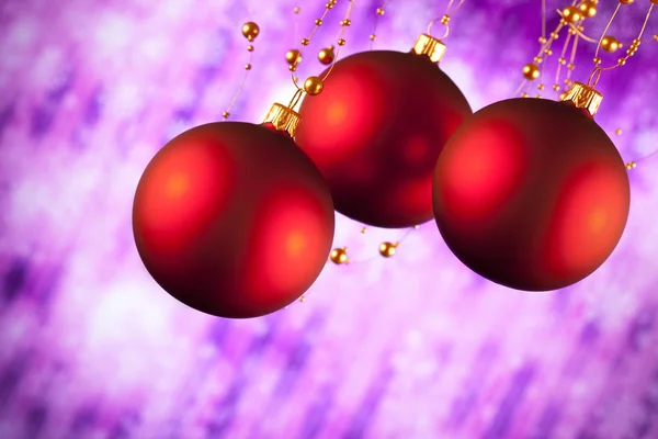 Три рождественских безделушки на фиолетовом фоне — стоковое фото