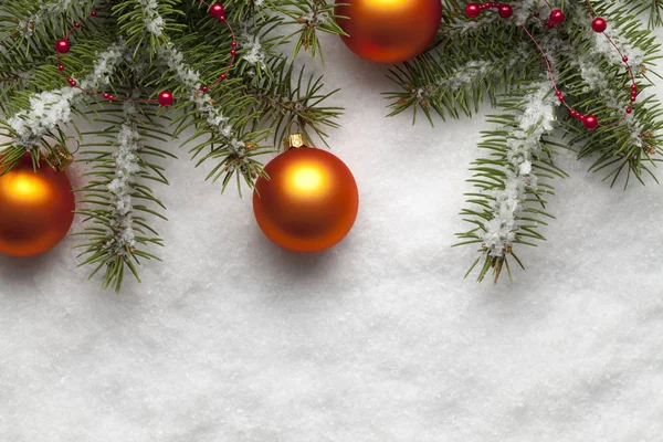 Ветки ели и рождественские шары на снежном фоне — стоковое фото
