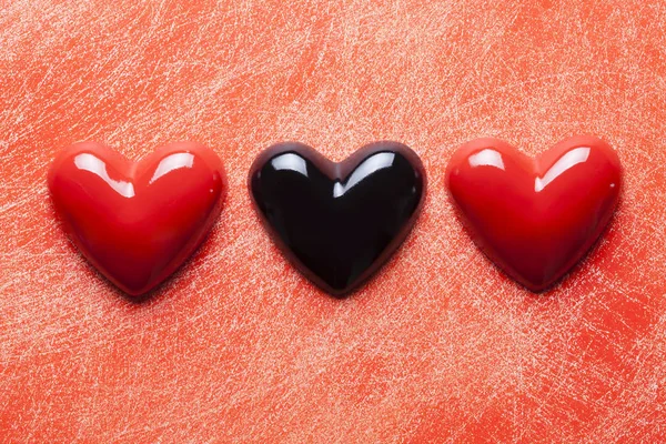 Два червоних і одне чорне серце на подряпаній поверхні — стокове фото