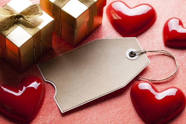 Etiqueta, caixas de presente e coração vermelho no fundo riscado — Fotografia de Stock