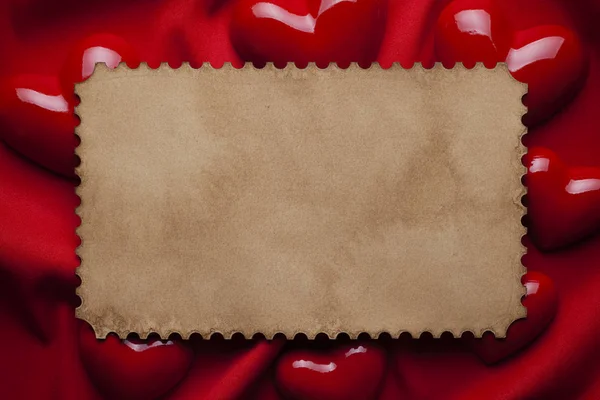 Folha de papel em branco e corações sobre fundo têxtil vermelho — Fotografia de Stock