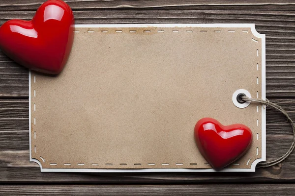 Κόκκινες καρδιές και κενό χαρτί ετικέτας στις ξύλινες σανίδες — Φωτογραφία Αρχείου