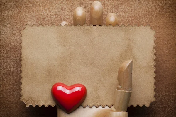 Порожній аркуш паперу в дерев'яній руці та червоному серці на папері backgrou — стокове фото