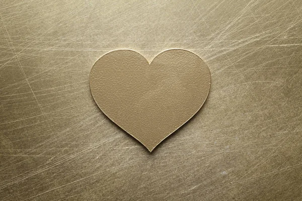 Golden metal heart on scratched surface