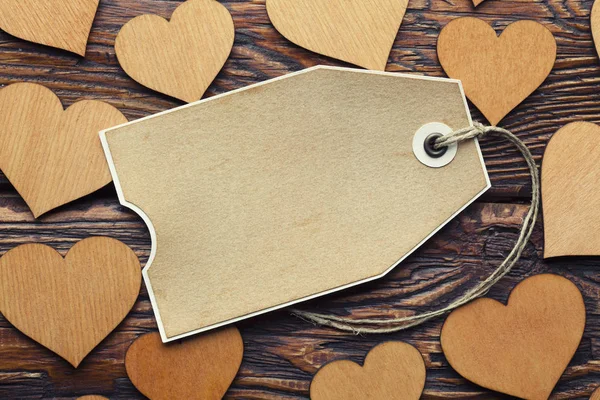 Etiqueta de papel em branco e corações de madeira em pranchas fundo — Fotografia de Stock