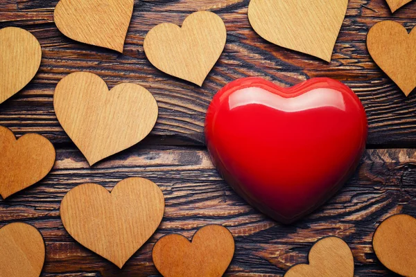 Corazón rojo y grupo de corazones de madera sobre mesa de madera — Foto de Stock