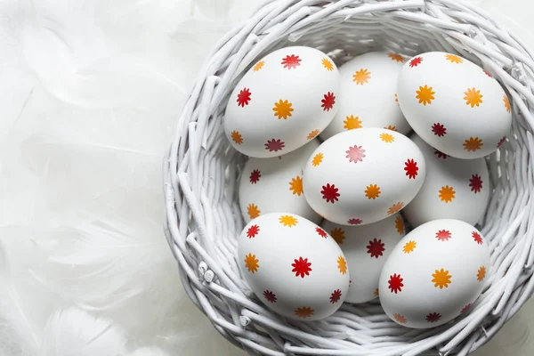 Uova di Pasqua modellate nel cestino e piume bianche — Foto Stock