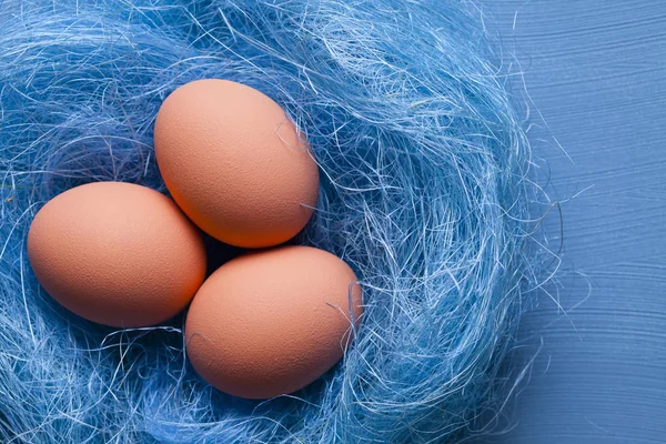 Tre påskägg i boet på blå bakgrund — Stockfoto